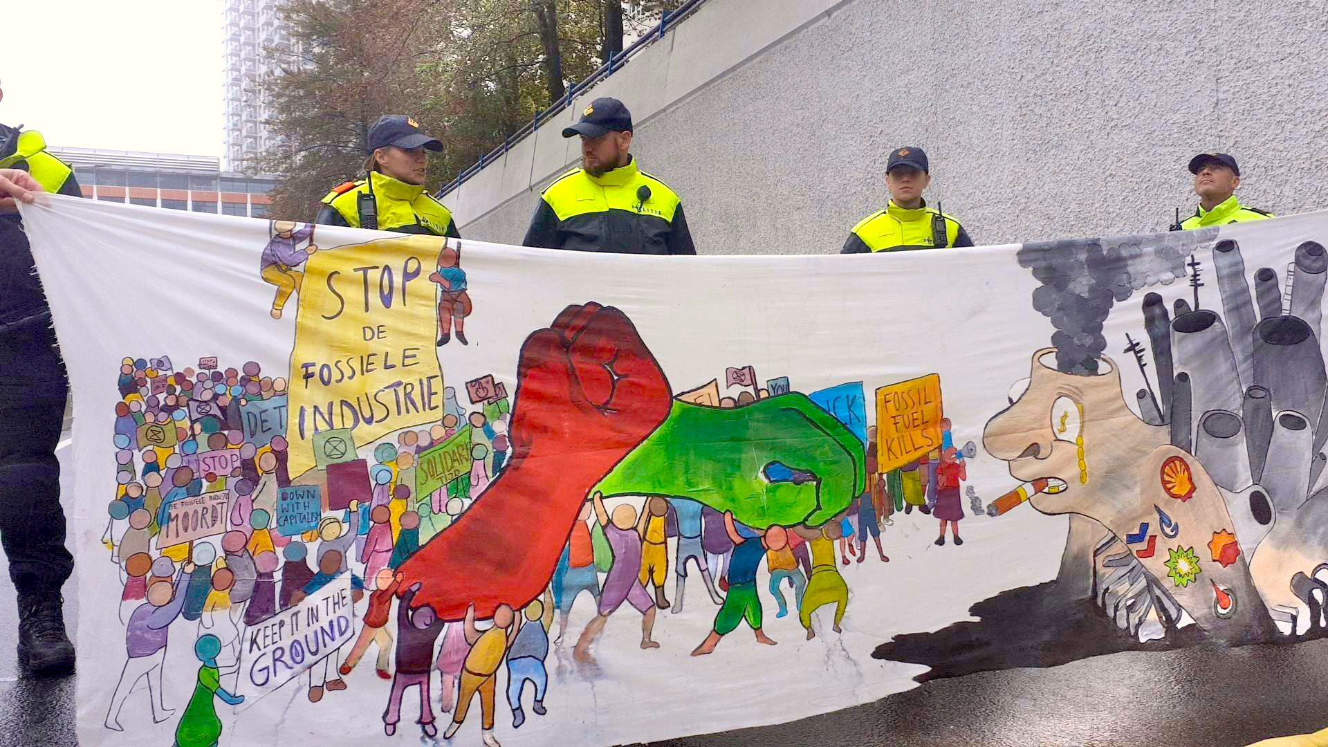 banner met tekst tegen de fosiele industrie staat voor een rij van politie agenten